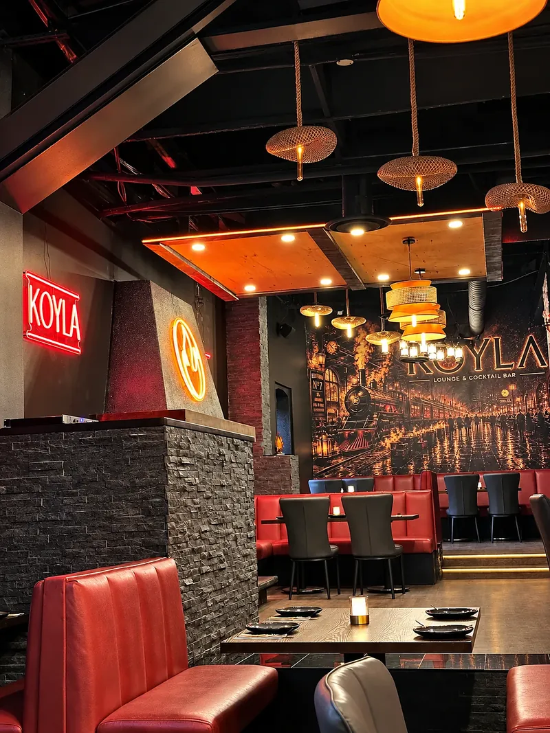 Red leather booths under the KOYLA neon and the train mural