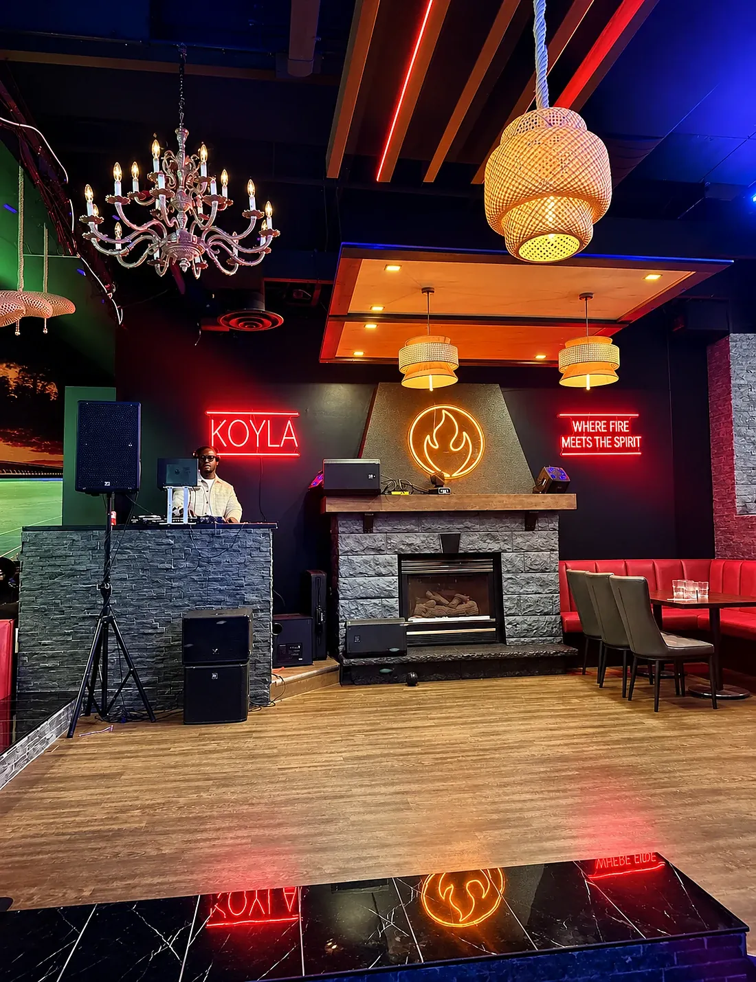 The stone fireplace with neon KOYLA and Where fire meets the spirit signs