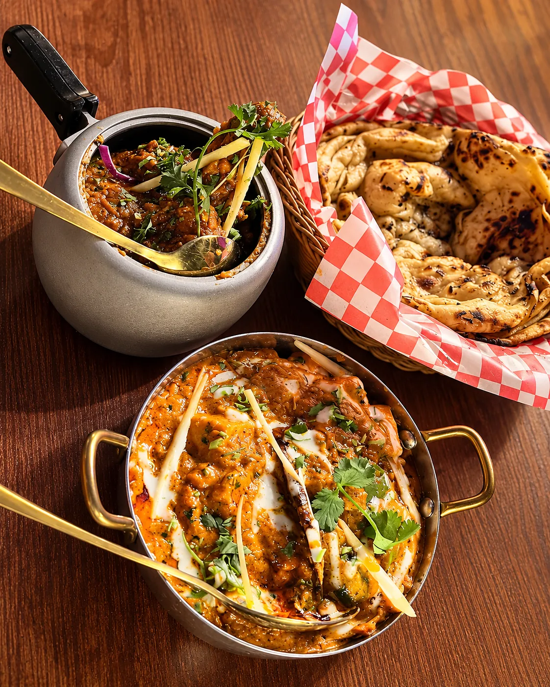 Handi chicken in a brass bowl with a curry pot and a basket of naan