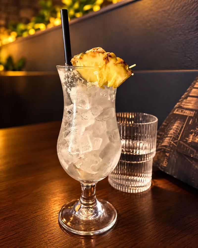 A pineapple-garnished drink over ice